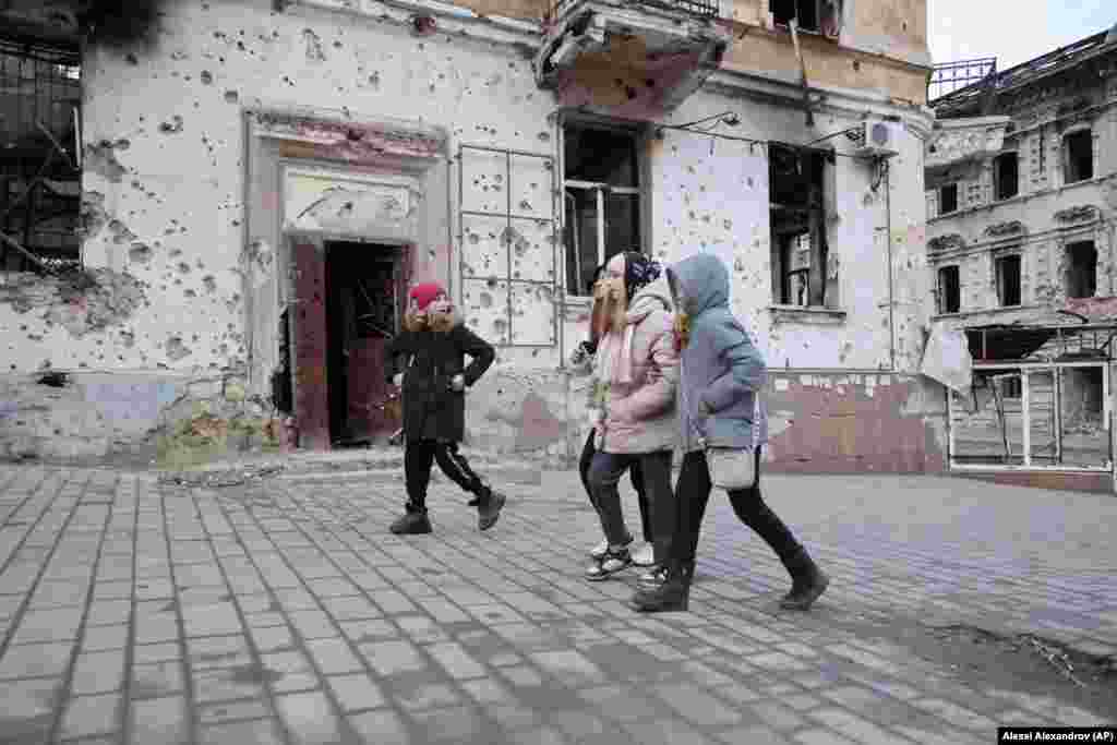 Діти проходять повз понівечені осколками будівлі в Маріуполі, 25 лютого 2023 року. Під час російської облоги загинули тисячі мирних жителів міста. Росія заявляє про 3000 вбитих мирних жителів, а Україна – про понад 25 000 загиблих