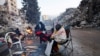 Люди согревается у костра, пока продолжаются поиски выживших после смертоносного землетрясения в Кахраманмараше, Турция, 13 февраля 2023 года.