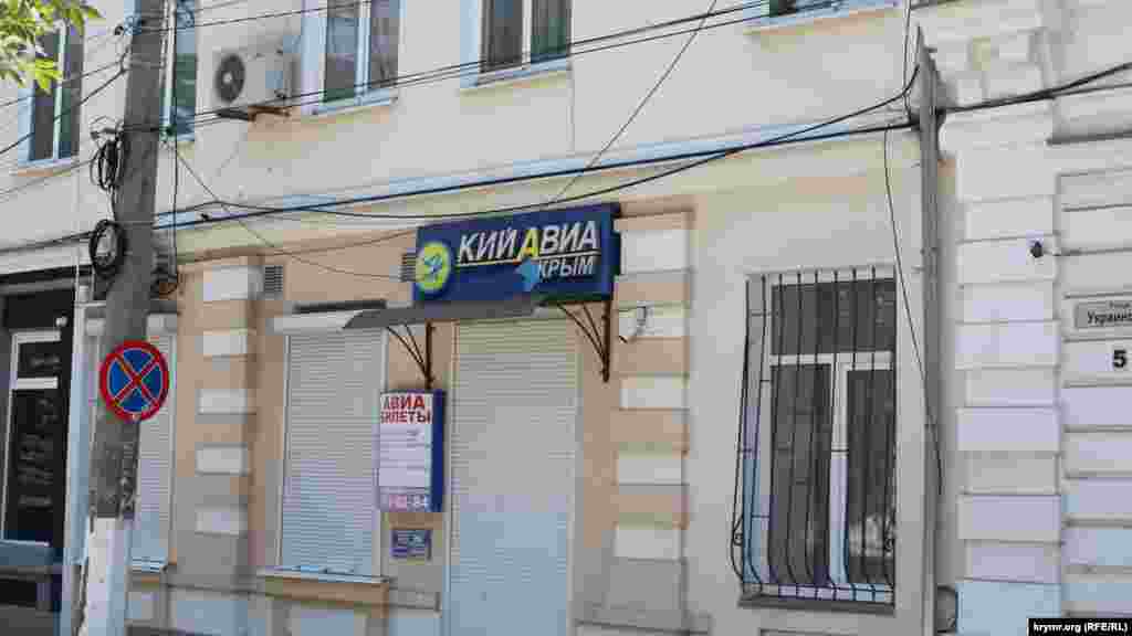 Kefeniñ merkezinde Ukrainskaya soqağında Kyiv-Aqmescit seferlerini kerçekleştirgen &laquo;Kiy-Avia&raquo; ava şirketiniñ levhası alâ daa&nbsp;bar
