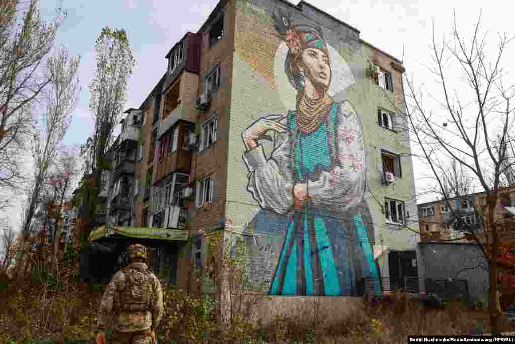 Esger diwaryna, entek uruşdan ozal, bir gyzyň şekli çekilen jaýyň golaýyndan geçip barýar. Donetsk sebitindäki Awdiýiwka şäheri, 2023-nji ýylyň noýabry.