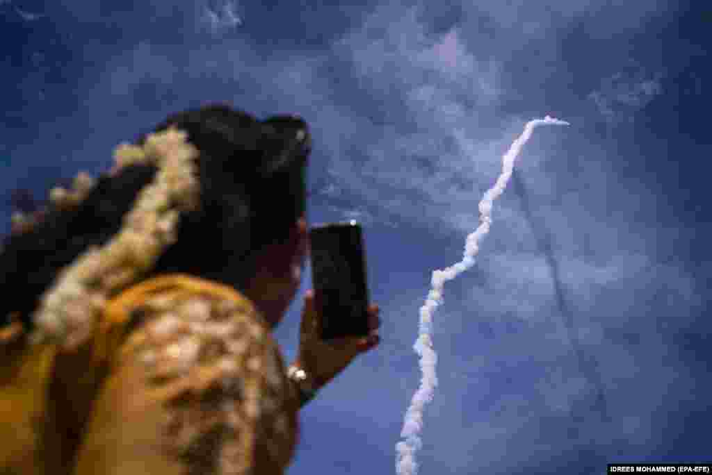Raýat Hindi kosmos gözleg guramasynyň (ISRO) Çandrayaan-3 (Aý ulagy-3) gämisiniň Satiş Dhawan kosmos merkezinden ýokary göterilişine tomaşa edýär. Hindistanyň günortasyndaky Andra Pradeş welaýatynda ýerleşýän Sriharikota, 2023-nji ýylyň 14-nji iýuly. 75 million dollardan az býudjet bilen gurlan guraly arkaly hindi kosmos gullugy aýa gonmaga we Amerikanyň Birleşen Ştatlary, öňki Sowet Soýuzy we Hytaý ýaly ýurtlaryň tejibesini gaýtalamaga synanyşýar. (EPA-EFE/IDREES MOHAMMED)