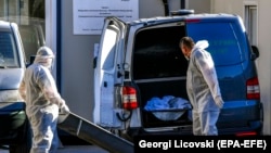 Dy persona duke bartuar trupin e pajetë të një personi të vdekur me koronavirus.