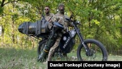 Luptători ucraineni pe o bicicletă electrică Delfast cu o armă antitanc.