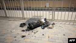The remnants of an Iranian missile intercepted over Qatar rest on the ground near a fence.