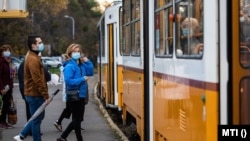 A koronavírus járvány miatt védőmaszkot viselő utasok a budapesti villamosmegállóban 2020. október 31-én.