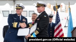 Віцеадмірал Берегової охорони США Макалістер (л), командувач ВМС ЗСУ Воронченко (п) і п'ятий президент Порошенко (позаду) під час урочистої церемонії передачі Сполученими Штатами Військово-морським силам України двох патрульних катерів класу Island. Балтимор, 27 вересня 2018 року
