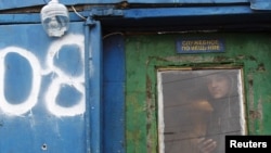 Täjigistanly migrant işçi gök-önüm satylýan bazarda ýerleşýän binanyň aýnasyndan daşaryk seredýär, 2011-nji ýylyň 11-nji noýabry.