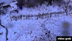 Видно кілька десятків тіл на тлі розбитої техніки
