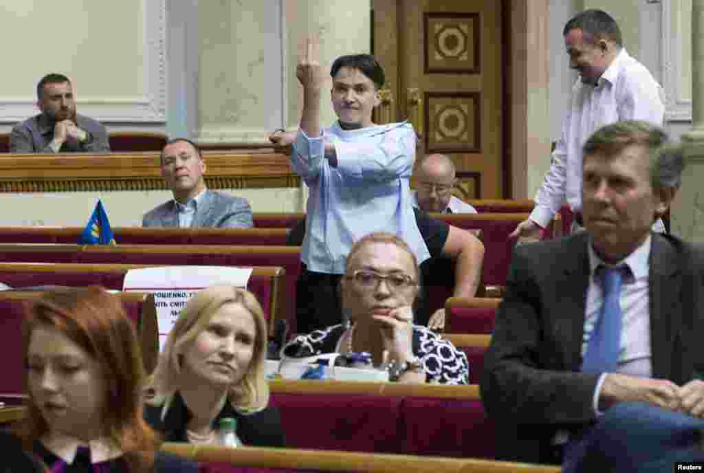 Украинаның Жоғарғы Рада отырысы кезінде депутат Надежда Савченко әдепсіз қылық көрсетіп тұр. 22 маусым 2017 жыл. Ресей түрмесінде отырған кезде украиналық әскери Надежда Савченко Мәскеудің агрессиясына қарсы ұлттық символға айналды. Кезінде оның Ресей сотын мазақтап, ортаңғы саусағын көрсеткен қылығы көпшілікке мәлім болған. Ал Украинаның азды-көпті еркін парламентіндегі қылығы оны даңққа бөлеген жоқ. Савченко Украинаға салтанатпен оралғанына бір жыл өткен кезде фотограф Владислав Мусиенко 22 маусымда парламент отырыстарын суретке тартып жүрген. Еліне оралған соң беделі түсіп кеткен Савченкоға украиналықтардың қалай қарайтыны жайлы Мусиенко ештеңе айтпады. Бірақ ол "әлгі сурет парламентте өзіңді бұлай ұстауға болмайтынын көрсететін фото деп санаймын" дейді.