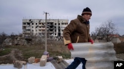 Бул киши кошунасына орус жана украин аскерлеринин ортосундагы салгылашуу учурунда талкаланган чатырын оңдоого жардам берип жатат. Архангельск айылы, 2022-жыл, 5-декабрь.