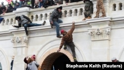 Прихильники Трампа піднімаються на стіну під час штурму будівлі Капітолію на мітингу проти визнання Конгресом США результатів президентських виборів 2020 року